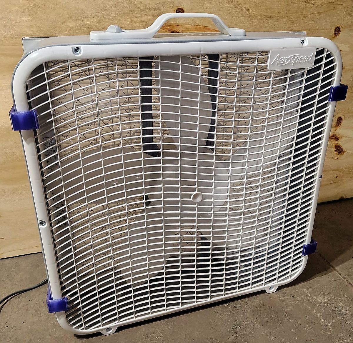The back of the box fan with the clips' short hooks over the moulded rim